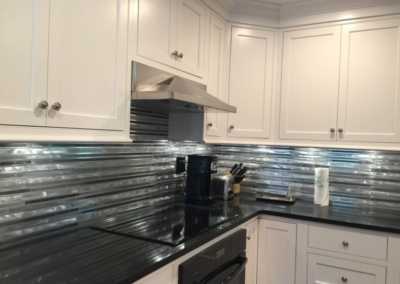stove and cabinets with a view of customized wrap around metal backsplash